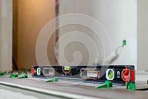 Tile levelling system, four plastic green clips with wedges. Close-up view, selective focus, blurred background