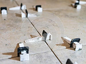 Tile levelling system with plastic clips and wedges. Close-up view, selective focus, blurred background.