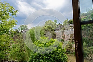 Tile-roofed buildings on riverside cliff in cloudy spring afternoon,China