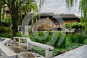 Tile-roofed wooden houses behind wayside garden in cloudy spring