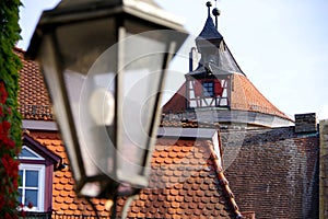 Tile roofs from the older house and a watchtower with a blurred street lamp in the foreground