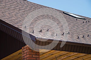 Tiled brown roof of new house with overflow, protection, from snow and fronton made of siding