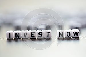 Tiled letter beads spelling â€œInvest nowâ€ text