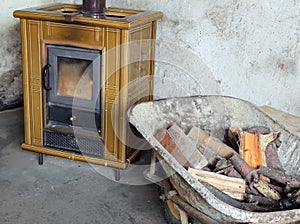 Tiled stove and wheelbarrow full of firewood in the old mountain