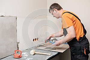 The tiler is applying adhesive to the kitchen wall to install the tile