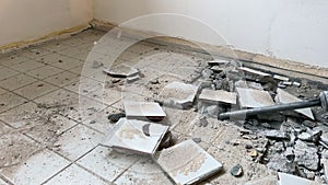 A tiler breaks old ceramic tiles with a jackhammer. Dismantling old tiles at a construction site