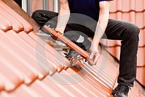 Tiler covering roof with new tile