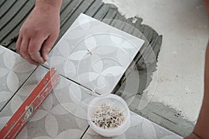 Tiler laying the ceramic tile on the floor. Professional worker makes renovation. Construction. Hands of the tiler