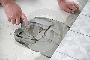 Tiler laying the ceramic tile on the floor. Professional worker makes renovation. Construction. Hands of the tiler.