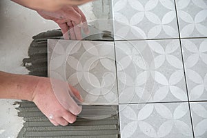 Tiler laying the ceramic tile on the floor. Professional worker makes renovation. Construction. Hands of the tiler