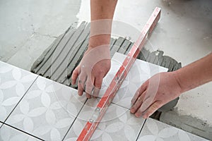 Tiler laying the ceramic tile on the floor. Professional worker makes renovation. Construction. Hands of the tiler