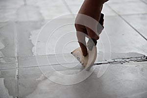 Tiler laying the ceramic tile on the floor. Professional worker makes renovation. Construction. Hands of the tiler