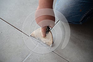 Tiler laying the ceramic tile on the floor. Professional worker makes renovation. Construction. Hands of the tiler