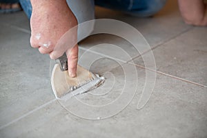 Tiler laying the ceramic tile on the floor. Professional worker makes renovation. Construction. Hands of the tiler