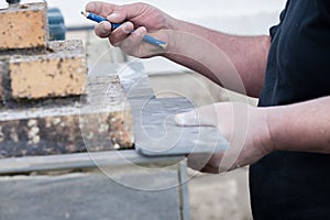 The mason measures and puts marks to cut and lay a tile