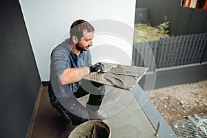 Tiler placing ceramic wall tile in position over adhesive with lash tile levelling system