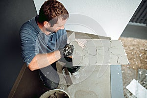 Tiler placing ceramic wall tile in position over adhesive with lash tile levelling system