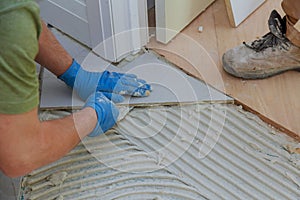 Tiler and plaster repair work laying tile, trowel in a man hand