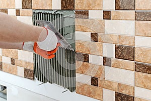 A tiler& x27;s hand is holding a notched trowel.