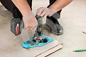 A tiler uses a caliper with a suction cup to drill holes in the tile