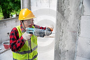 Tiler using electric impact drill to drilling cement wall at unfinished house construction
