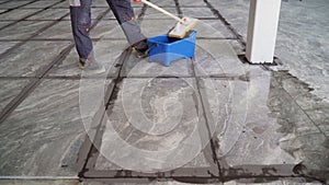 The tiler washes the tiles on the floor after work. A worker cleans large-format ceramic tiles on the floor with a brush