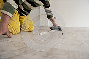 Tilers filling the space between ceramic wood effect tiles photo