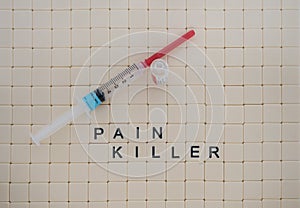 Tiles in a Row Spelling Pain Killer with Syringe and Vial