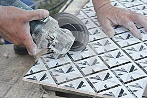 Tiling a bathroom. A man is cutting a bathroom ceramic tile with a disc angle grinder