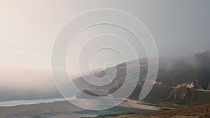 Tilt down onto a windswept beach in Big Sur as evening mist settles in