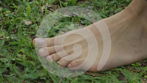 Tilt down shot of a woman standing barefoot and feeling the grass