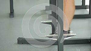 Tilt down of a young bearded man with a bare torso doing leg lifting on a horizontal bar in a gym