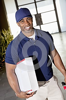 Tilt image of a happy African American delivery man looking at camera