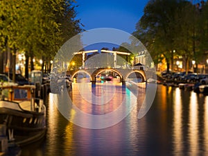 Tilt shift image of skinny bridge on canal in Amsterdam