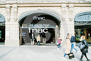 Tilt-shift lens used over pedestrians walking in front of FNAC electronics and bookstore mall in central Paris on Champs