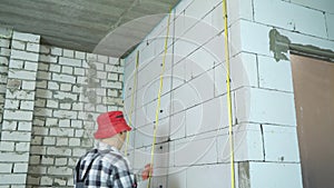 Tilt shot of builder installing metal rails onto clamps on block wall