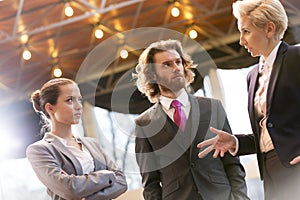 Tilt shot of mature businesswoman discussing with colleagues while standing at office