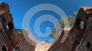 Tilt, Tilt Shot. Plane Flying Over Ruins, Leaving Contrail In Blue Sky. Plane, Clear Sunny Sky Background. Airplane