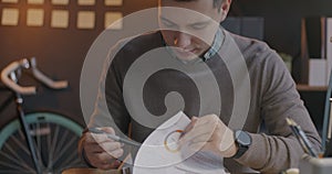 Tilt-up portrait of confident businessman working with document then looking at camera and smiling in office at night