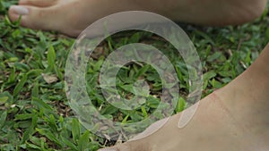 Tilt up shot of a woman standing barefoot and feeling the grass