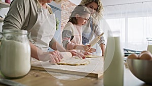 Tilt up video of three generations of women rolling dough.