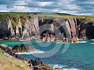 Tilted strata of red sandstone sedimentary bedrock cliffs in Pembrokeshire, Wales, UK