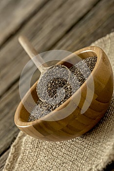 Tilted view of small wooden bowl full of chia seeds