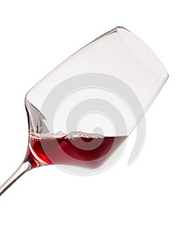 Tilted wine glass with red wine. Isolated on white. Close-up.