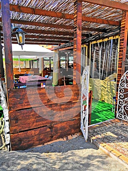 Timber bar stools and table sitting on the sand beside a set of stairs leading to a beachfront restaurant