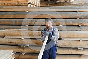 Timber harvesting for construction. Carpenter stacks boards. Industrial background. Authentic workflow