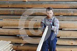 Timber harvesting for construction. Carpenter stacks boards. Industrial background. Authentic workflow.