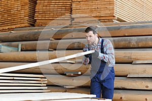 Timber harvesting for construction. Carpenter stacks boards. Industrial background. Authentic workflow
