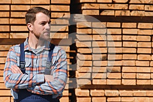 Timber harvesting for construction. Carpenter stacks boards. Industrial background. Authentic workflow.