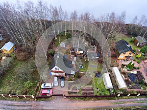 Timber house with courtyard, barns and small garden is on lake shore. Aerial view at spring season. Russia